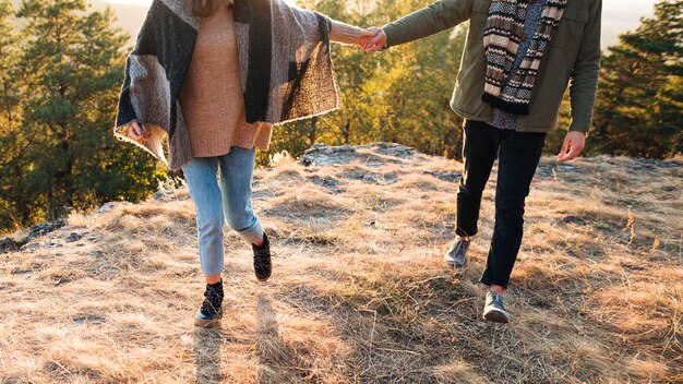 Young man and woman holding hands outdoors