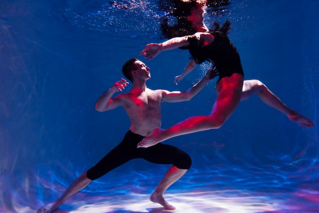 Free photo young man and woman posing together while submerged underwater