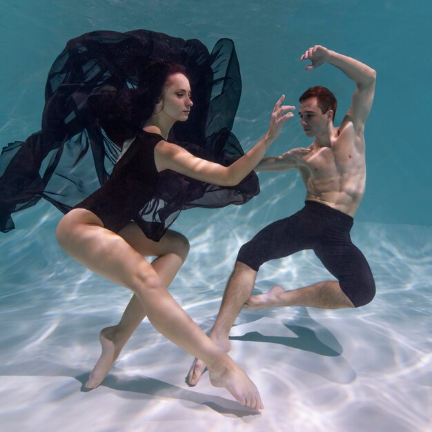 Young man and woman posing together while submerged underwater