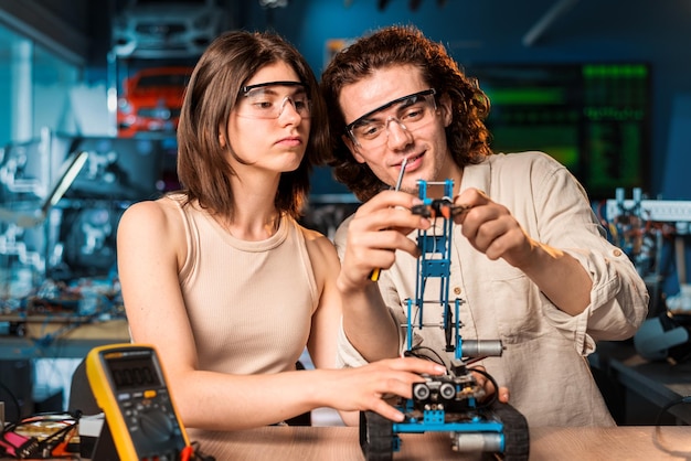 Free photo young man and woman in protective glasses doing experiments in robotics in a laboratory robot