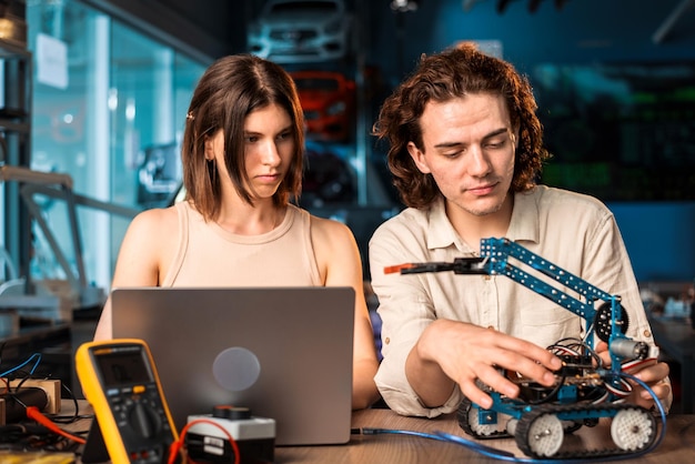 Free photo young man and woman in protective glasses doing experiments in robotics in a laboratory