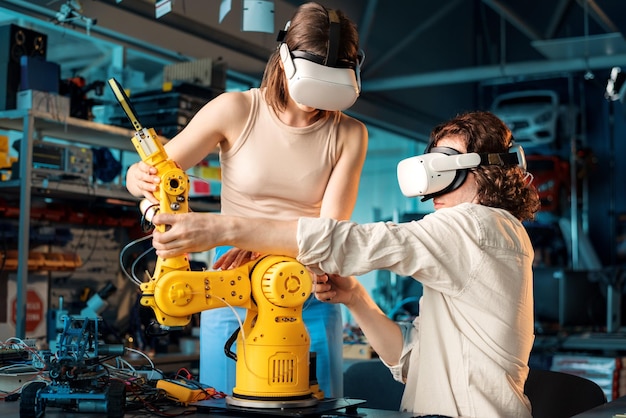 Free Photo young man and woman in vr glasses doing experiments in robotics in a laboratory robot and tools