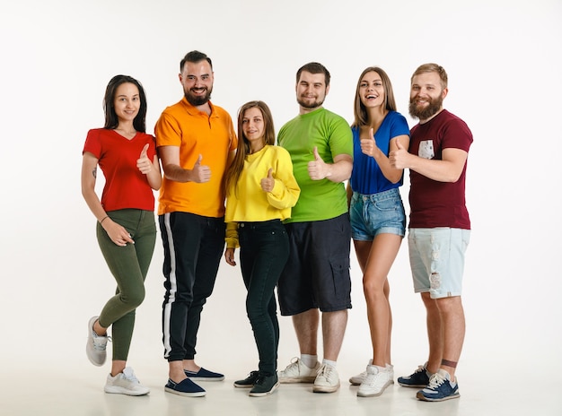 Free Photo young man and woman weared in lgbt flag colors on white wall. caucasian models in bright shirts. look happy, smiling and hugging. lgbt pride, human rights and choice concept.