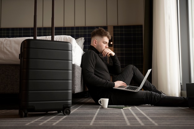 Free photo young man working on his laptop in a hotel room