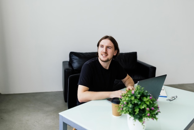 Young man working at home with laptop and papers on desk