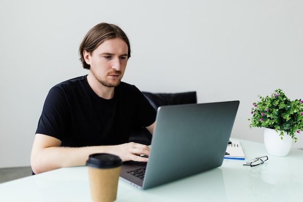 Young man working at home with laptop and papers on desk