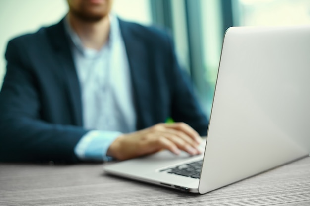 Young man working with laptop, man's hands on notebook computer, business person at workplace