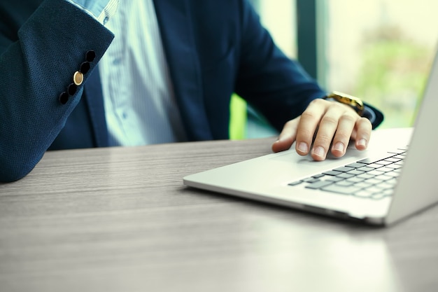 Young man working with laptop, man's hands on notebook computer, business person at workplace