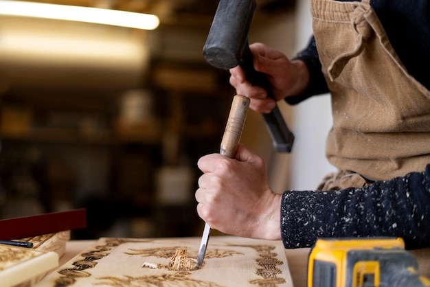 Free photo young man working in a wood engraving workshop