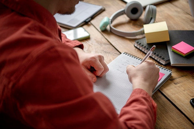 Free photo young man writing on a notebook during study session