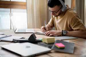 Free photo young man writing on a notebook during study session