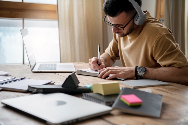 Free Photo young man writing on a notebook during study session