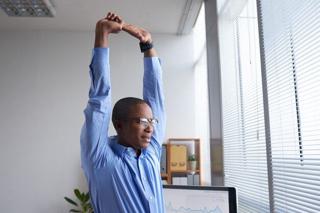 Young manager doing a good stretch before work looking at the window