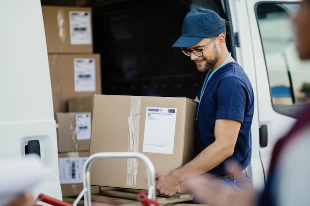 Free photo young manual worker unloading cardboard boxes from a delivery van