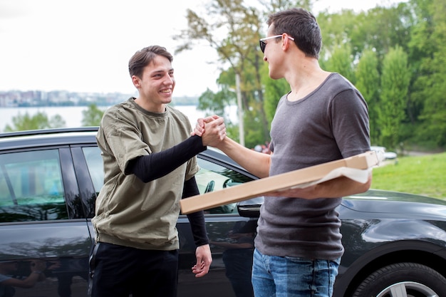 Free Photo young men greeting in nature near car