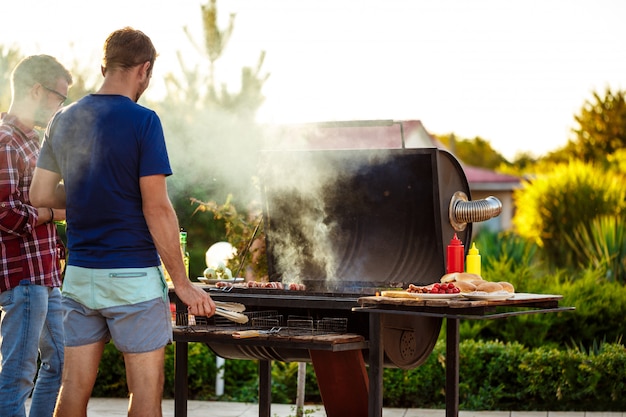 Free Photo young men roasting barbecue on grill in cottage countryside.