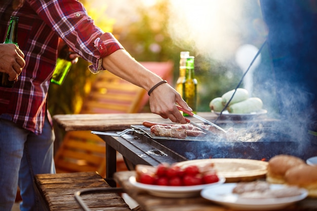 Young men roasting barbecue on grill in cottage countryside.