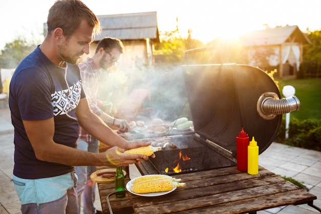 Young men roasting barbecue on grill in cottage countryside.