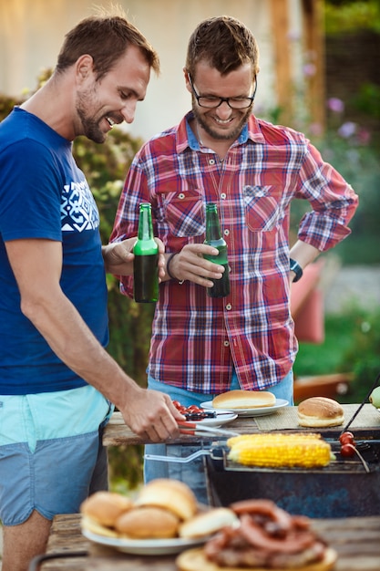 Free photo young men roasting barbecue on grill in cottage countryside.