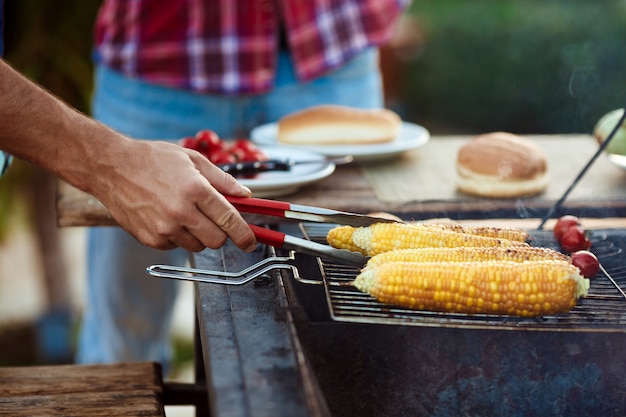 Young men roasting barbecue on grill in cottage countryside.