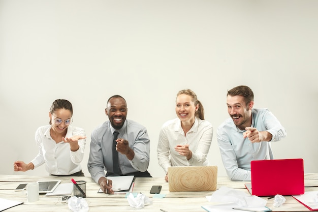 Young men and women sitting at office and working on laptops. Emotions concept