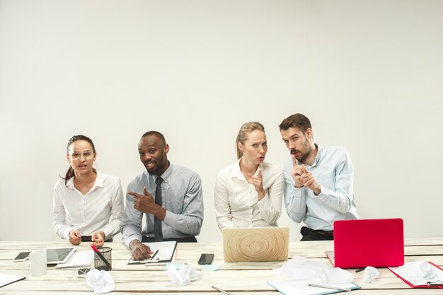 Young men and women sitting at office and working on laptops. Emotions concept