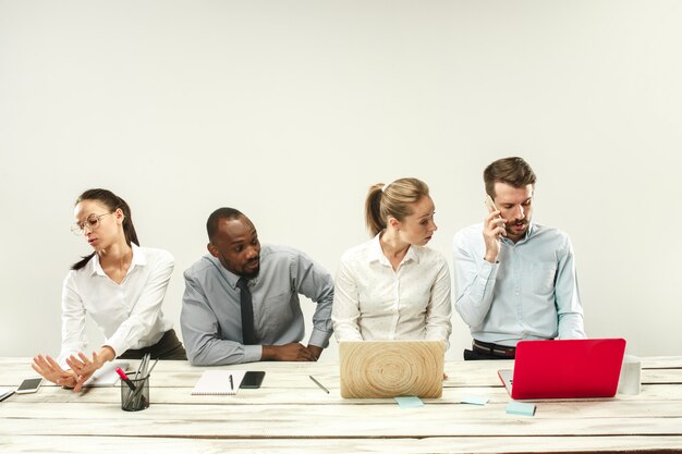 Young men and women sitting at office and working on laptops. Emotions concept