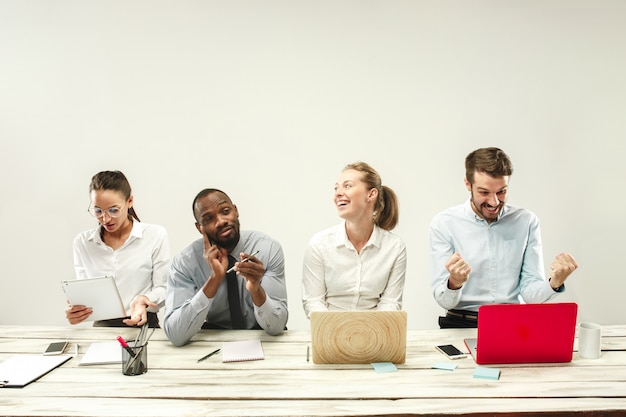 Young men and women sitting at office and working on laptops. Emotions concept