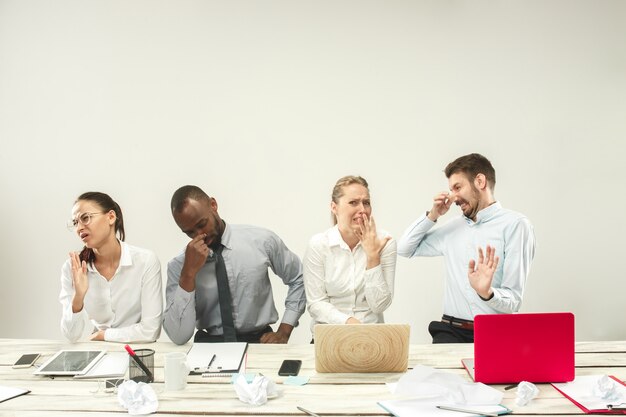 Young men and women sitting at office and working on laptops. Emotions concept