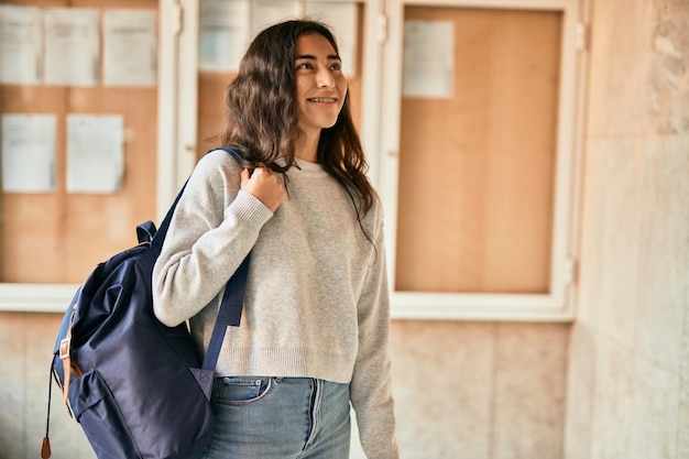 Young middle east student girl smiling happy holding book at the city.