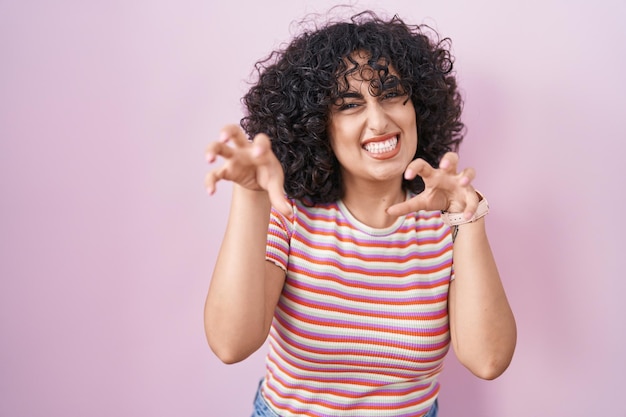 Free photo young middle east woman standing over pink background smiling funny doing claw gesture as cat aggressive and sexy expression