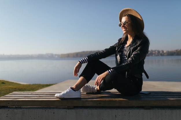 Young model girl woman posing in autumn day at the lake waterfront dressed up in casual clothes