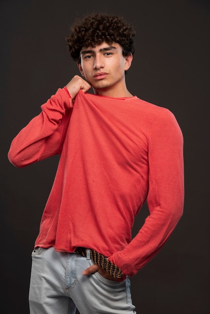 Young model in red shirt posing by putting hands on his neck. 