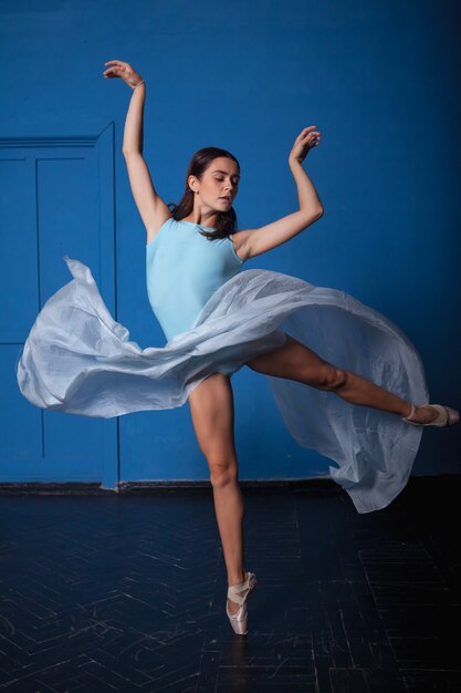 Young modern ballet dancer posing on blue