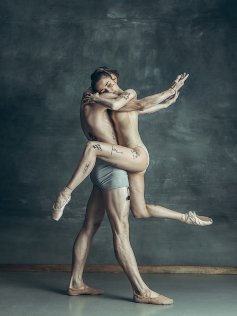 young modern ballet dancers posing on gray