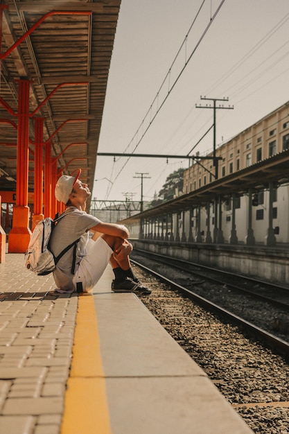 Free photo young modern boy waiting by the platform for the train to arrive