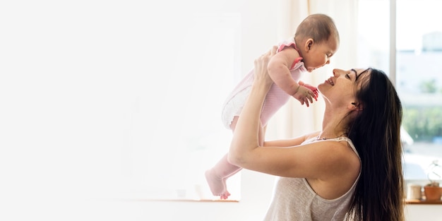 Free photo young mom holding her baby in the air blank space