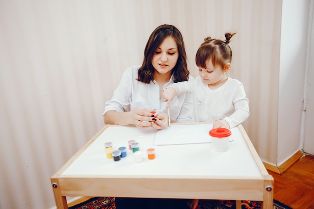 Free photo a young mother, along with her little daughter paints on paper