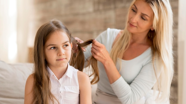 Free photo young mother braiding her daughters hair at home