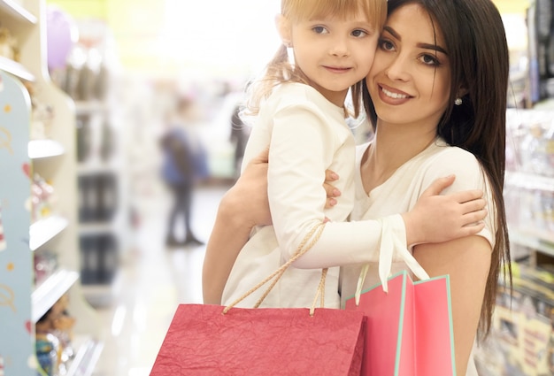 Young mother and daughter posing in shopping center.