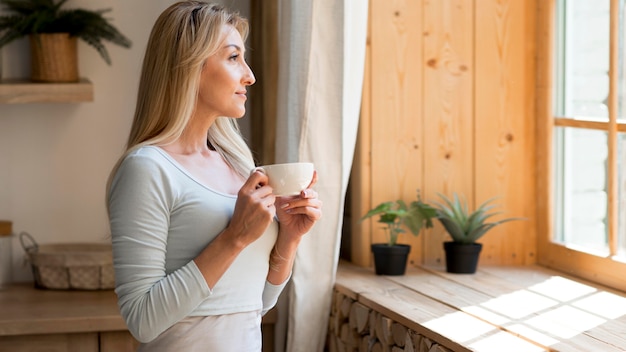 Young mother enjoying a cup of coffee while looking through window