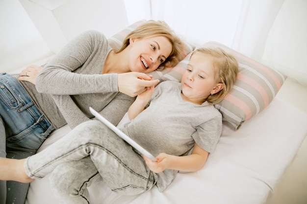 Young mother and her little daughter at home at sunny morning. Soft pastel colors. Happy family time on weekend. Mother's Day concept. Family, love, lifestyle, motherhood and tender moments concepts.