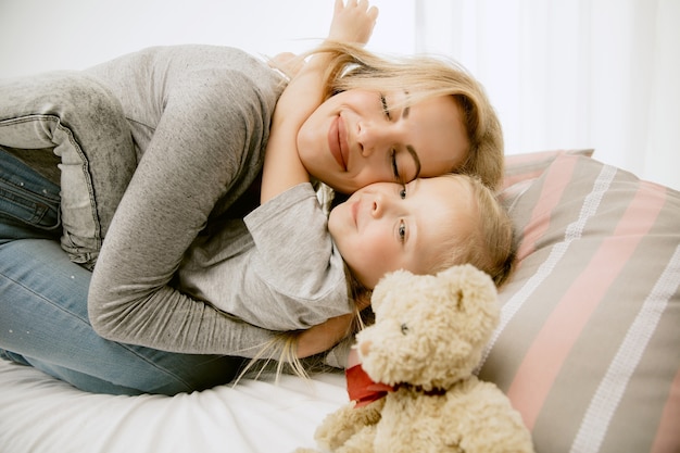 Free photo young mother and her little daughter at home at sunny morning. soft pastel colors. happy family time on weekend.