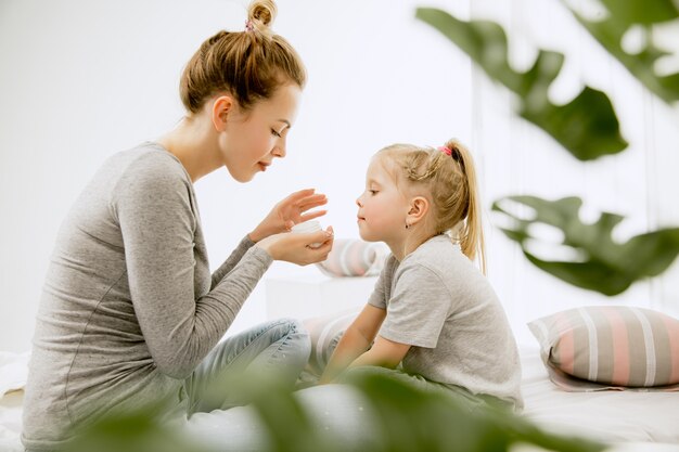 Young mother and her little daughter at home at sunny morning.