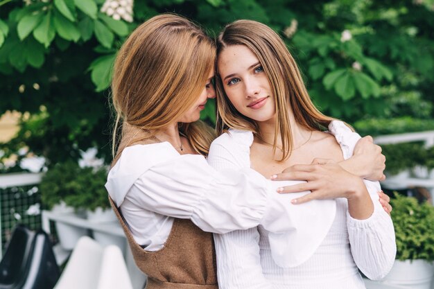 A young mother kisses and hugs her beautiful daughter