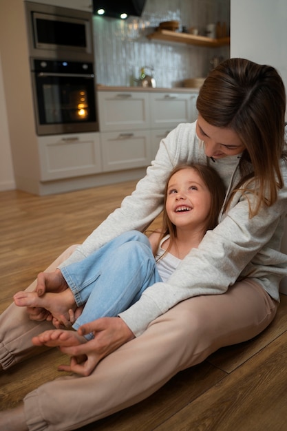 Young mother making her daughter laugh by tickling her