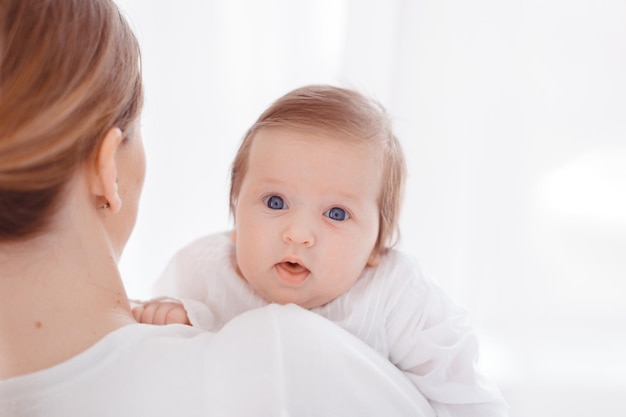 Young mother and newborn baby in white bedroom