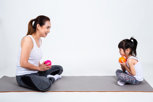 Young mother playing with cute daughter on white background