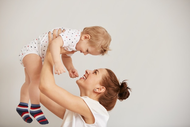 Young mother playing with her little baby on the bed