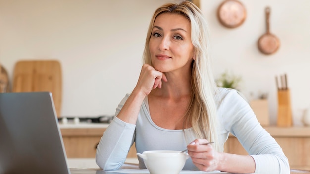 Free photo young mother posing while working and having breakfast at home